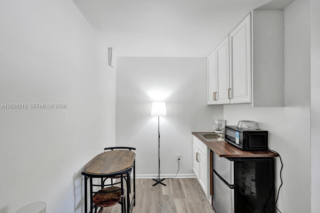 A small kitchenette features white cabinets, a wood countertop, a mini-fridge, and a dining set — 1422 US Highway 441, Okeechobee FL 34974, OKEECHOBEE, FL