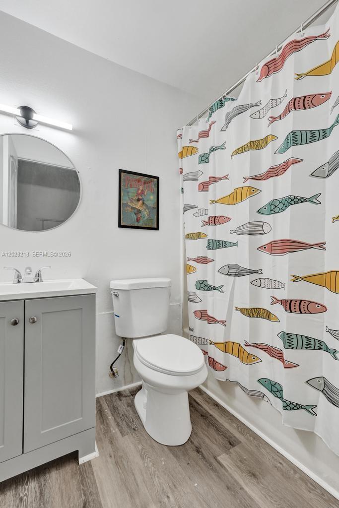 A bathroom features a gray vanity, a round mirror, a toilet, and a fish-patterned shower curtain — 1422 US Highway 441, Okeechobee FL 34974, OKEECHOBEE, FL