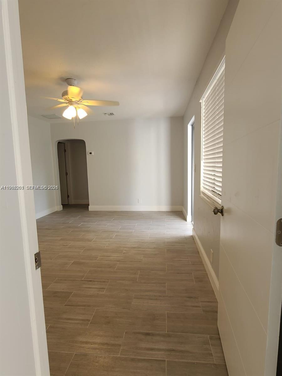 An interior view shows a room with light-colored tile flooring, a ceiling fan, and an arched doorway — 2008 NE 4th Ave # R, Wilton Manors FL 33305, WILTON MANORS, FL