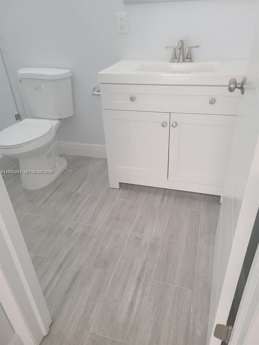 A small bathroom features a white vanity, a toilet, and light gray wood-look tile flooring — 2008 NE 4th Ave # R, Wilton Manors FL 33305, WILTON MANORS, FL