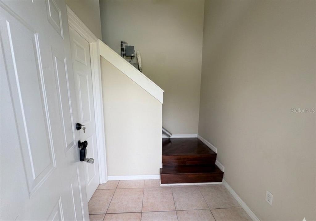 An entryway features tile flooring, a white door, and two dark wood steps leading upward — 100 KINGBIRD CIRCLE UNIT 1, DAYTONA BEACH, FL