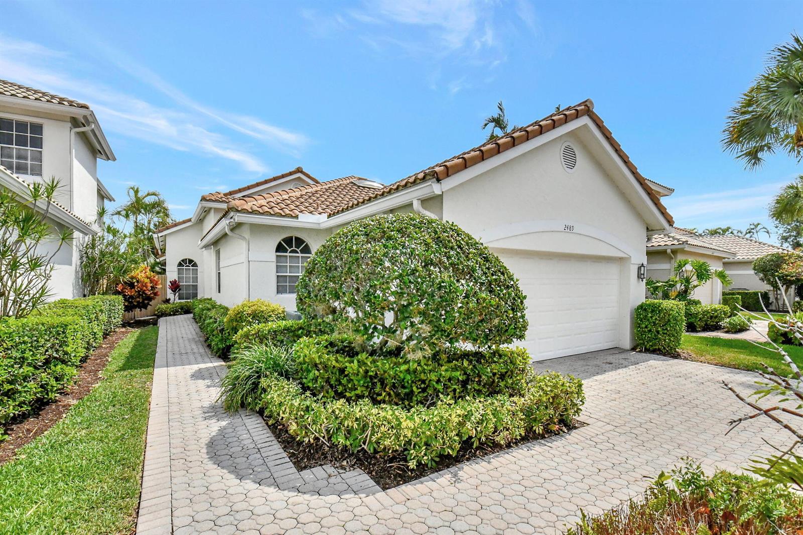 A white house with a tiled roof, a paved driveway, and a manicured front garden — 2489 NW 66th Drive, Boca Raton FL 33496, BOCA RATON, FL