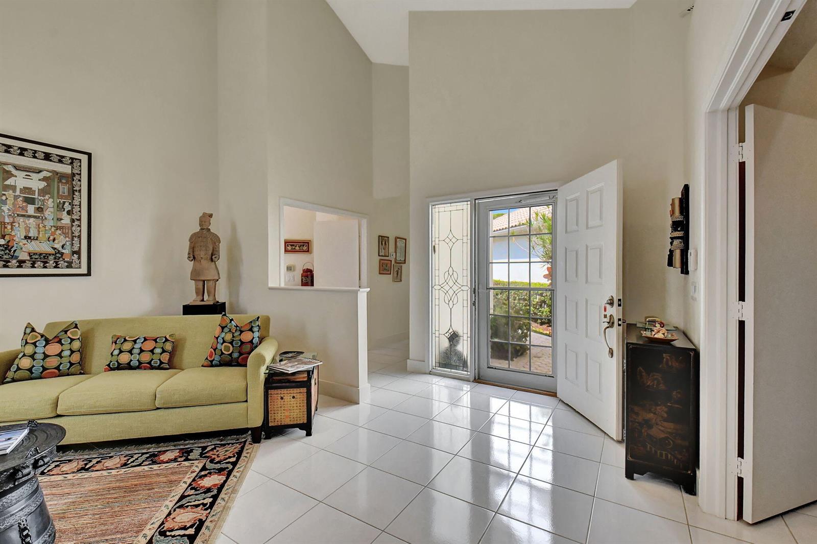 A bright entryway features white tile floors, a vaulted ceiling, and a light green sofa — 2489 NW 66th Drive, Boca Raton FL 33496, BOCA RATON, FL