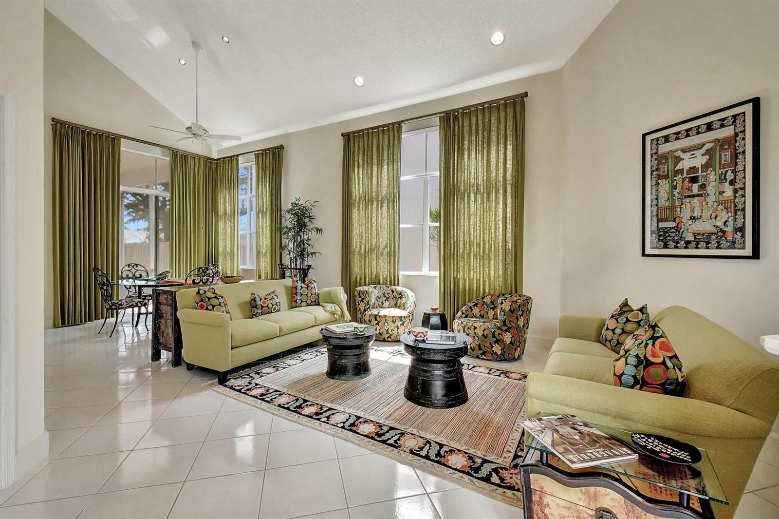 A living room with two lime green sofas, patterned armchairs, and floor-to-ceiling olive green curtains — 2489 NW 66th Drive, Boca Raton FL 33496, BOCA RATON, FL