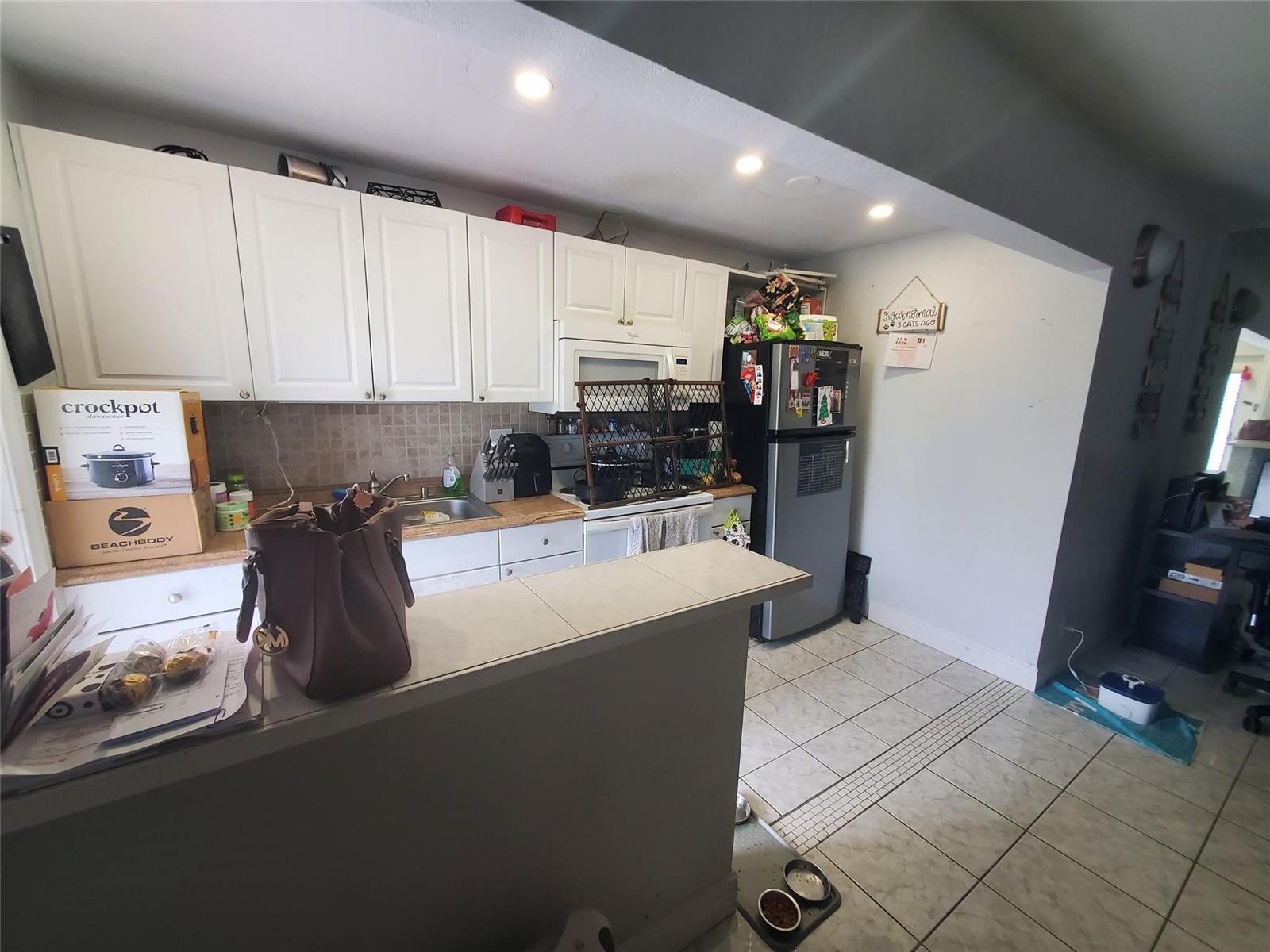 A kitchen features white cabinets, a tiled countertop, a stainless steel refrigerator, and tile flooring — 1021 NE 24th Avenue # 30, Pompano Beach FL 33062, POMPANO BEACH, FL