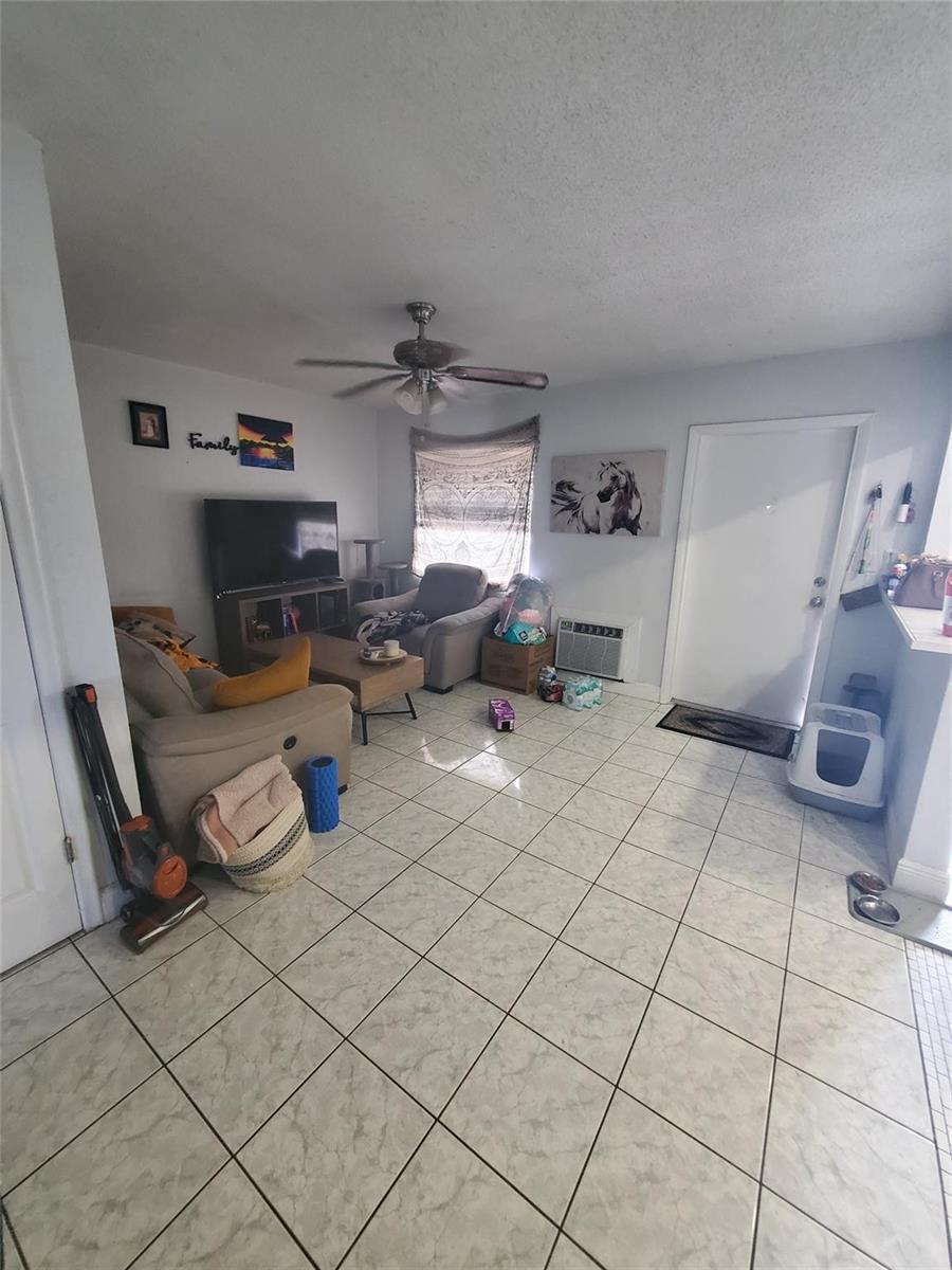 A living room features light-colored tile flooring, a ceiling fan, and a television area — 1021 NE 24th Avenue # 30, Pompano Beach FL 33062, POMPANO BEACH, FL