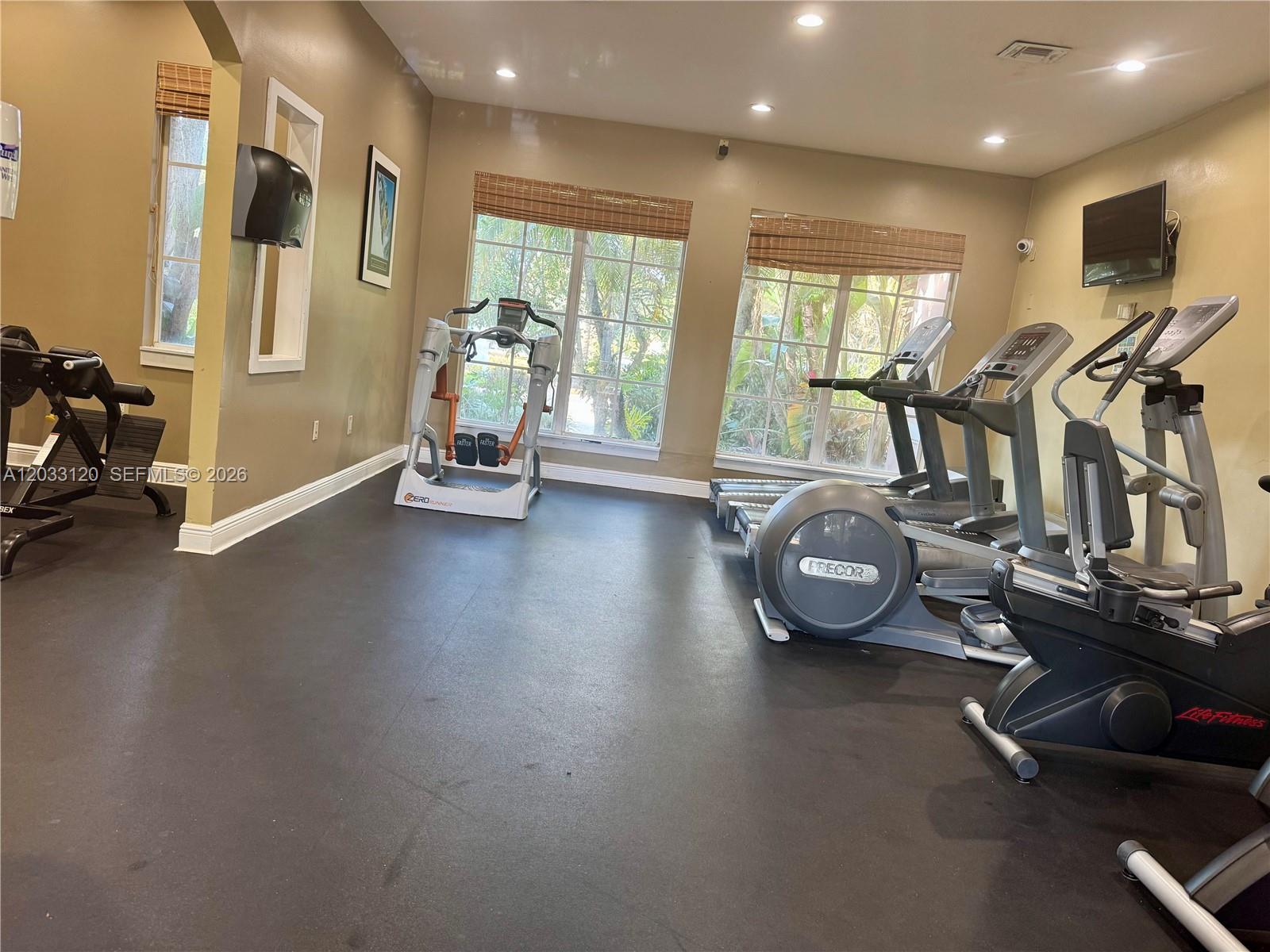 This gym features rubber flooring, multiple cardio machines, and large windows with bamboo shades — 12142 Saint Andrews Pl # 107, Miramar FL 33025, MIRAMAR, FL