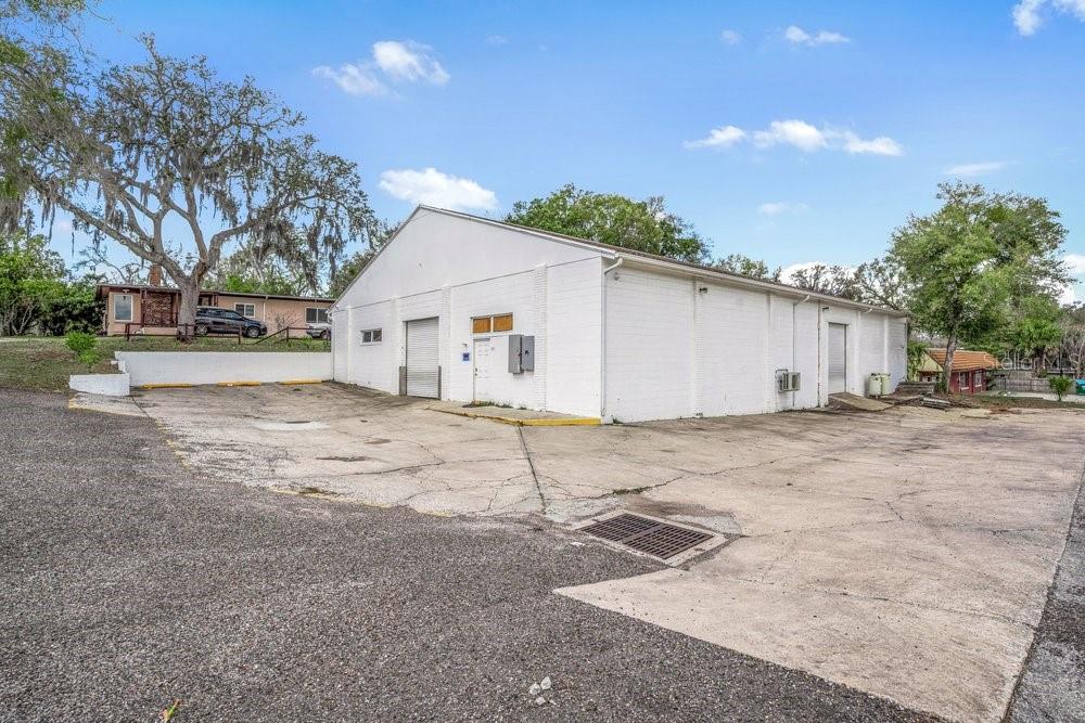 A white, single-story commercial building with a concrete parking lot and multiple exterior doors — 103 HIGHLAND STREET, ORANGE CITY, FL