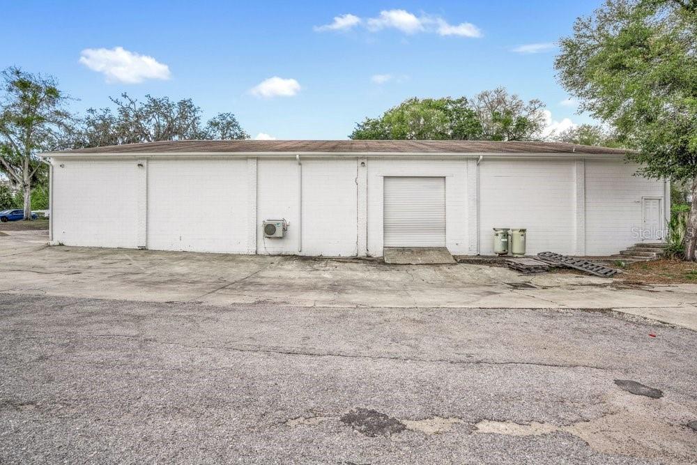 A white, single-story industrial building with a roll-up door and a paved parking lot — 103 HIGHLAND STREET, ORANGE CITY, FL
