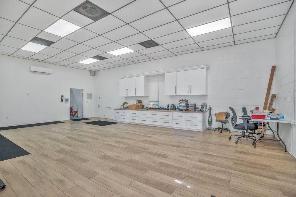 An office space with white walls, a drop ceiling, wood-look flooring, and white cabinetry — 103 HIGHLAND STREET, ORANGE CITY, FL