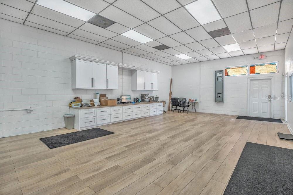A commercial office space features white cabinetry, wood-look flooring, and a drop ceiling — 103 HIGHLAND STREET, ORANGE CITY, FL