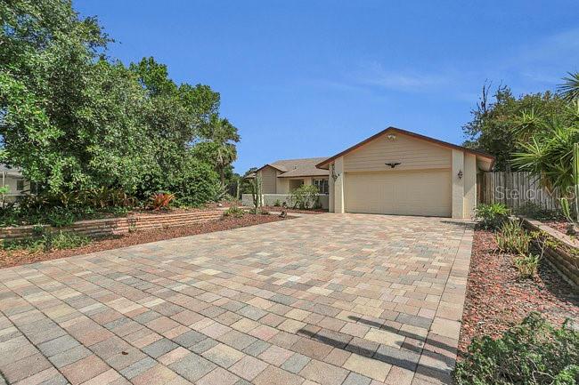 A single-story house with a beige garage and a large paved driveway — 9319 WOODBREEZE BOULEVARD, WINDERMERE, FL