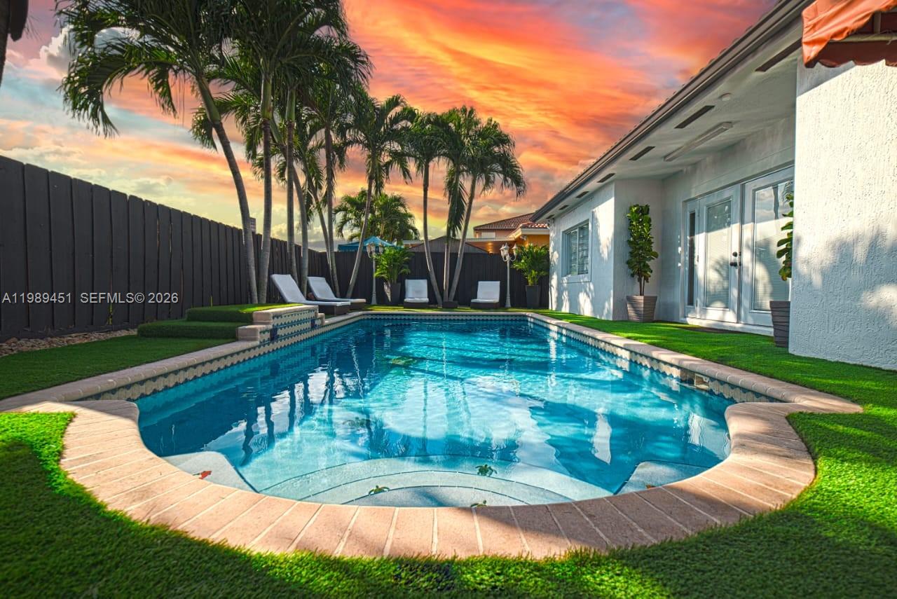A backyard swimming pool with artificial turf, lounge chairs, and palm trees at sunset — 10254 SW 227th St # 0, Cutler Bay FL 33190, CUTLER BAY, FL