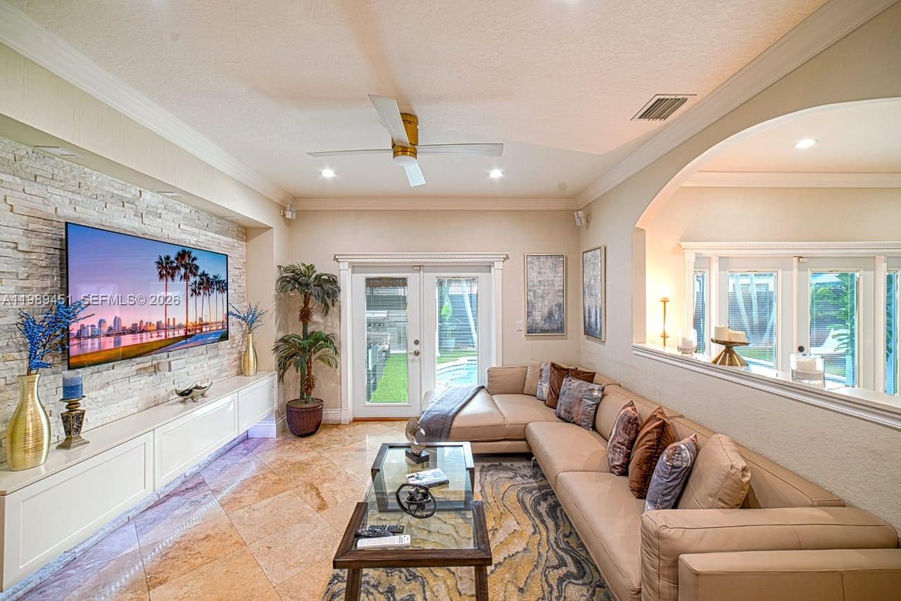 A living room features a stone accent wall, a large television, and a leather sectional — 10254 SW 227th St # 0, Cutler Bay FL 33190, CUTLER BAY, FL