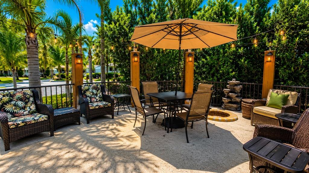A patio features a dining set under an umbrella, wicker chairs, and string lights — 219 E APPALOOSA TRAIL, RIVER RANCH, FL
