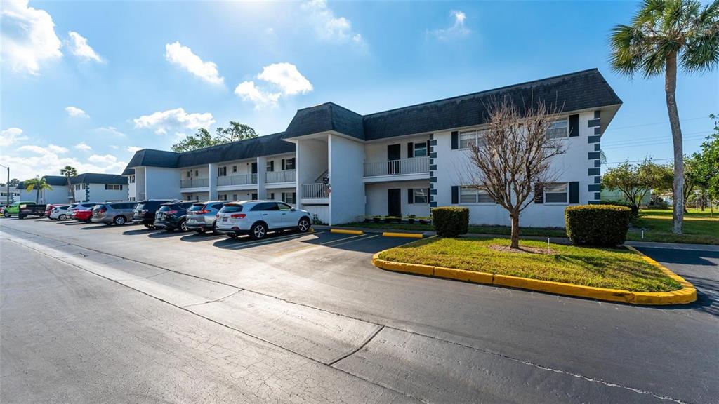 A multi-story apartment building with a parking lot and a palm tree in front — 202 46TH AVENUE TERRACE W UNIT 409, BRADENTON, FL