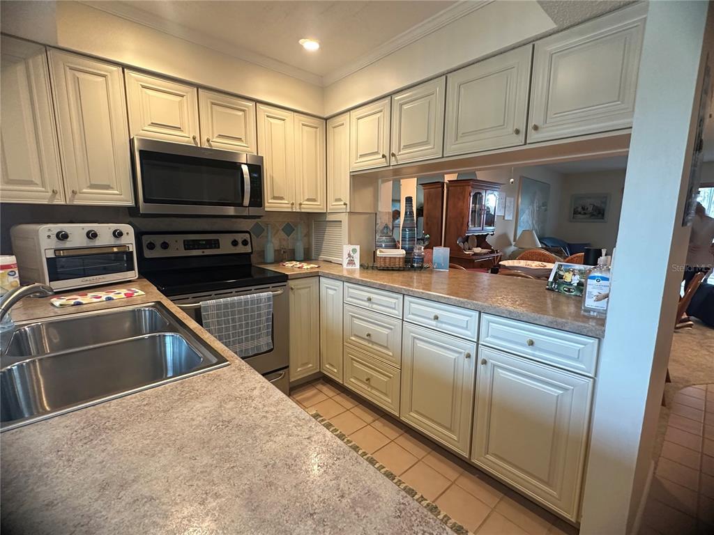 A kitchen features off-white cabinets, stainless steel appliances, and laminate countertops — 202 46TH AVENUE TERRACE W UNIT 409, BRADENTON, FL