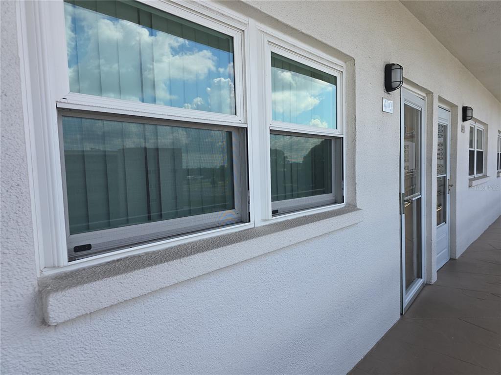 A white stucco exterior wall features two windows and a glass-paneled door with a number — 5603 80TH STREET N UNIT 410, ST PETERSBURG, FL