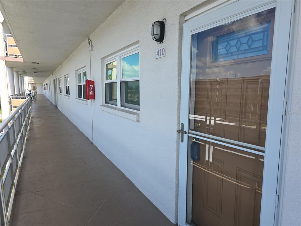 An exterior view of an apartment building hallway with a numbered door and windows — 5603 80TH STREET N UNIT 410, ST PETERSBURG, FL