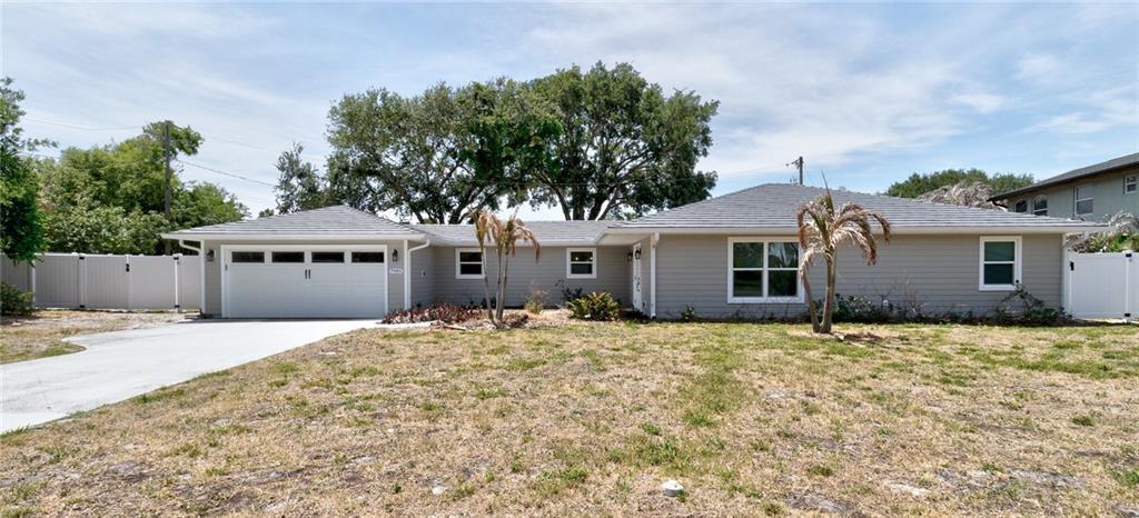 A single-story house with gray siding, a two-car garage, and a large front yard — SEBASTIAN, FL