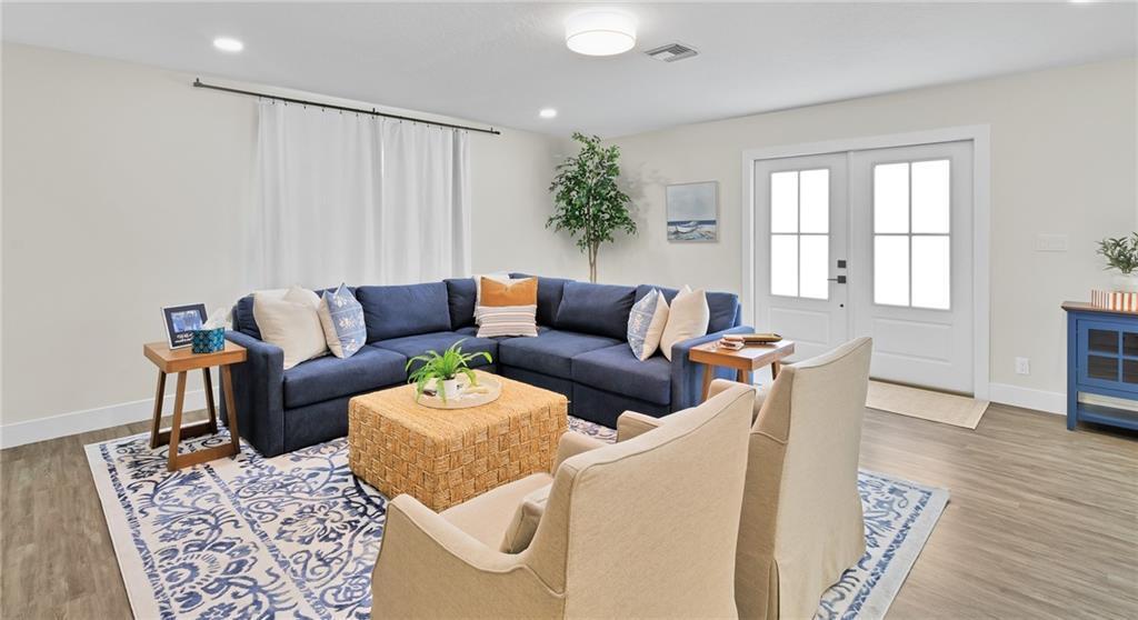A living room features a blue sectional sofa, two beige armchairs, and a patterned rug — SEBASTIAN, FL