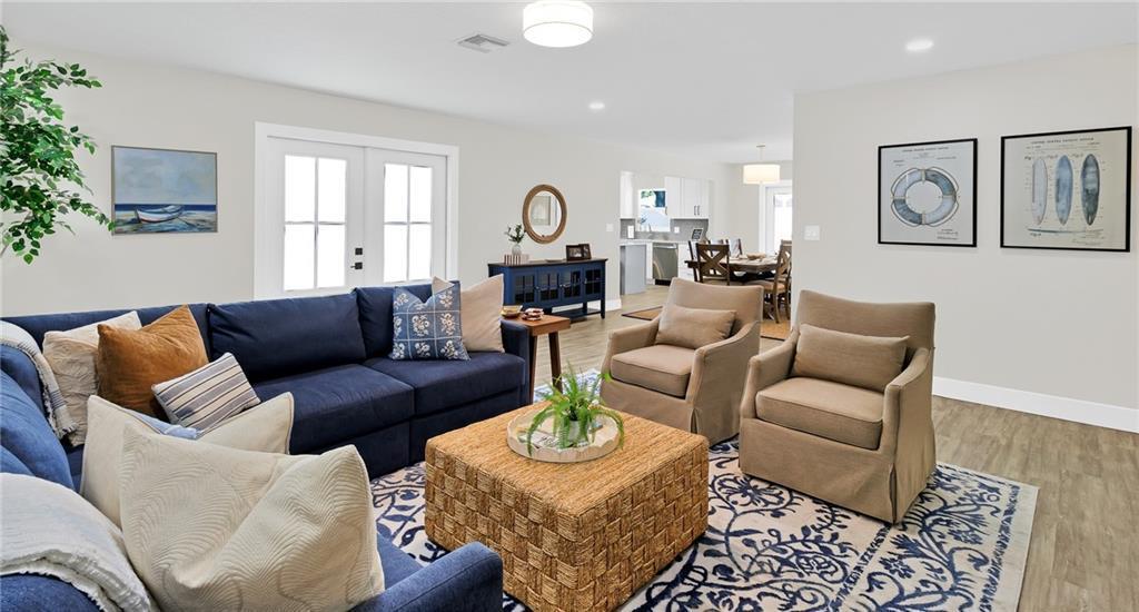 A living room features a blue sofa, two beige armchairs, and a woven coffee table — SEBASTIAN, FL