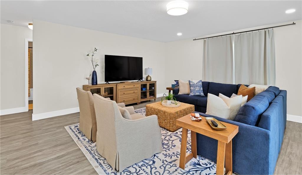 A living room features a blue sectional sofa, two beige armchairs, and a wood media console — SEBASTIAN, FL