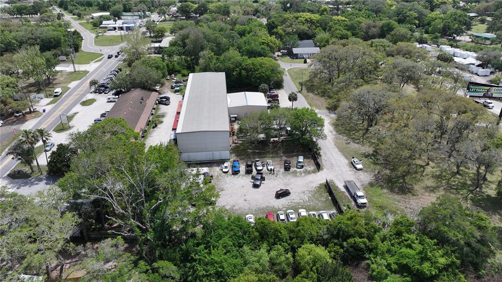 An aerial view shows a commercial warehouse building surrounded by parking lots and wooded areas — 1324 MATTIE STREET, ST AUGUSTINE, FL