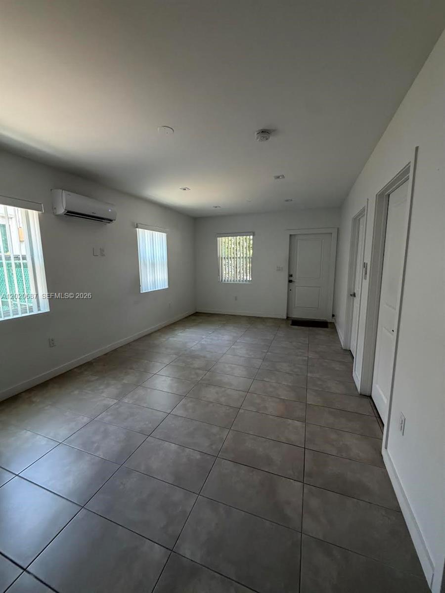 A bright, empty room features light-colored tile flooring, white walls, and a wall-mounted air conditioner — 2333 SW 58th Ave # 2333, Miami FL 33155, MIAMI, FL