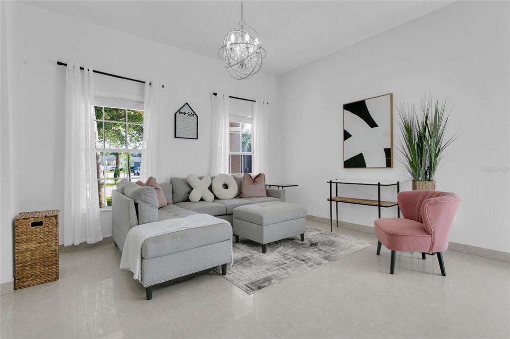 A living room features a gray sectional sofa, a pink armchair, and a crystal chandelier — 4034 FELDSPAR TRAIL, ORLANDO, FL