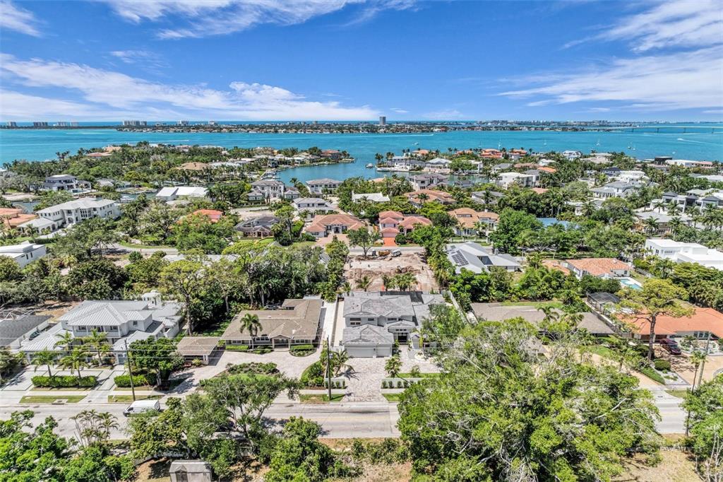 An aerial view shows a coastal neighborhood with houses, lush trees, and a distant bay — 1395 HARBOR DRIVE, SARASOTA, FL