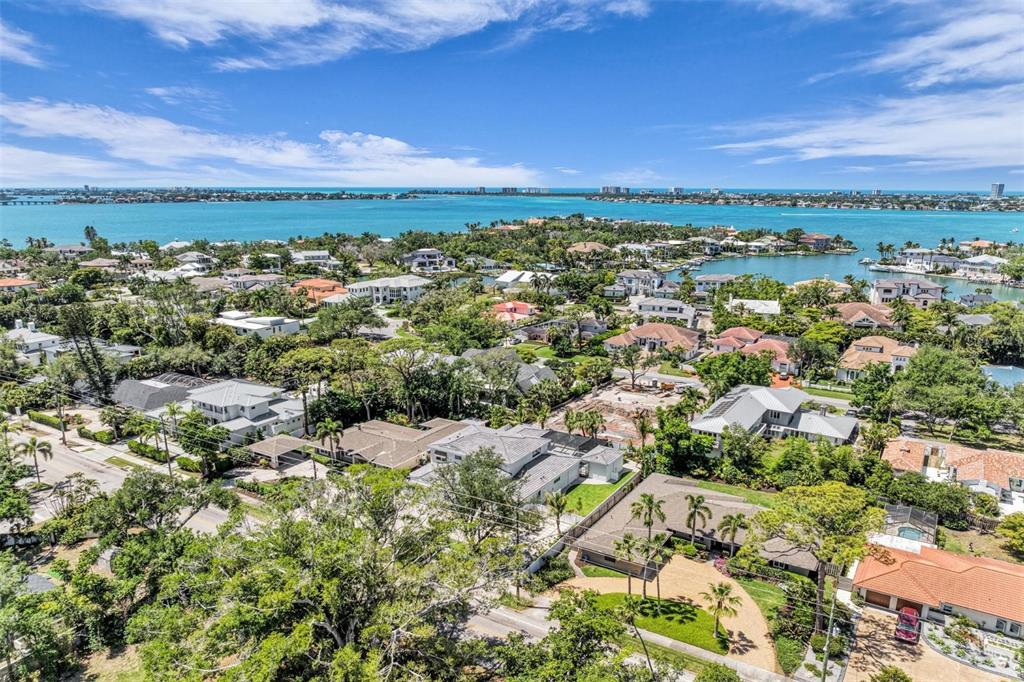 An aerial view shows a coastal neighborhood with houses, lush trees, and a large bay — 1395 HARBOR DRIVE, SARASOTA, FL