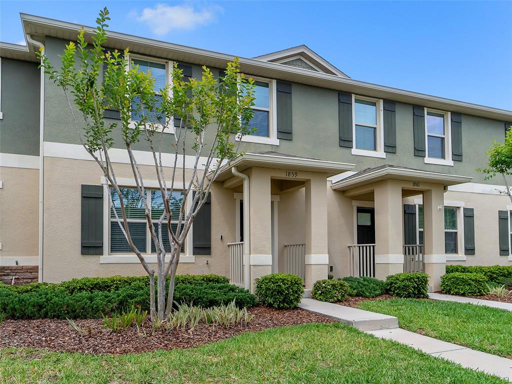 The exterior of a two-story townhouse features tan stucco walls, dark shutters, and covered entryways — 1859 RED CANYON DRIVE, KISSIMMEE, FL