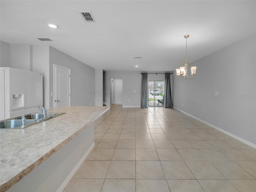 A kitchen island with a sink overlooks an open dining area with tile flooring — 1859 RED CANYON DRIVE, KISSIMMEE, FL