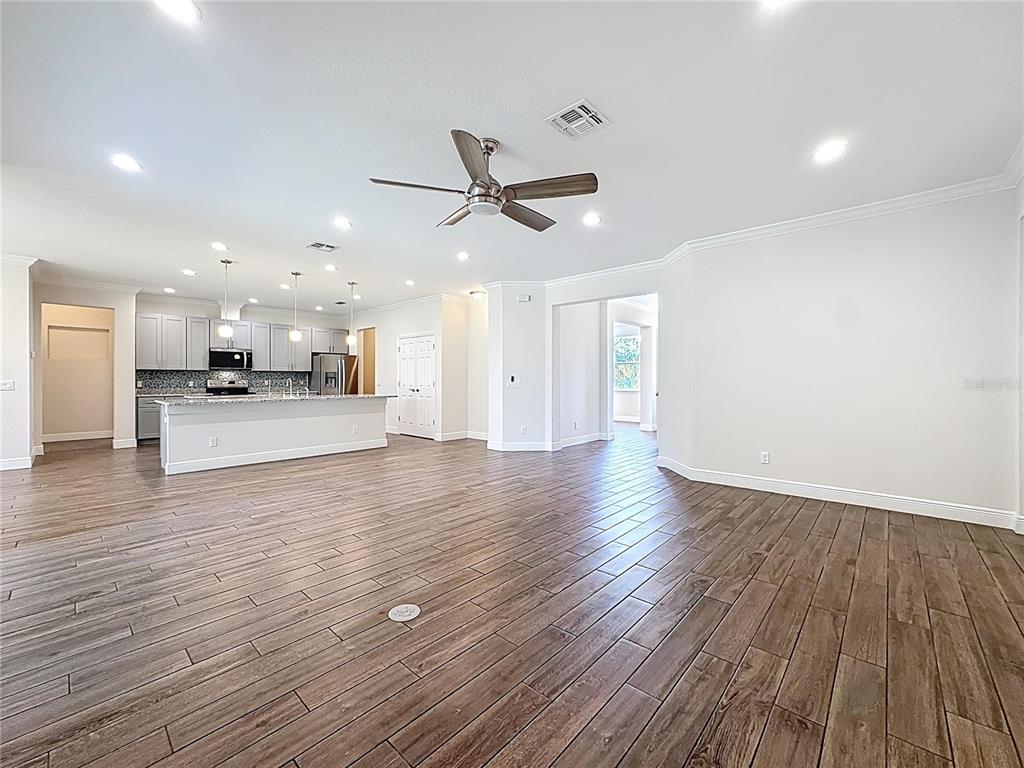 An open-concept living area features wood-look tile flooring, a kitchen with an island, and recessed lighting — 3110 CARNEGIE AVENUE, ORLANDO, FL