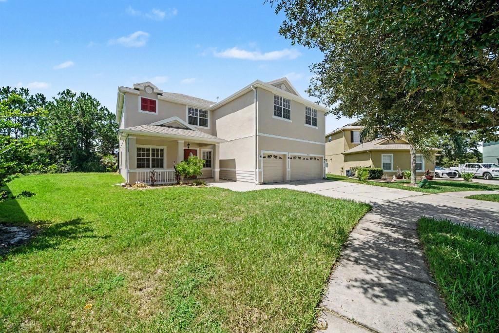 A two-story suburban house with a beige stucco exterior, a two-car garage, and a lawn — 20009 OAKFLOWER AVENUE, TAMPA, FL