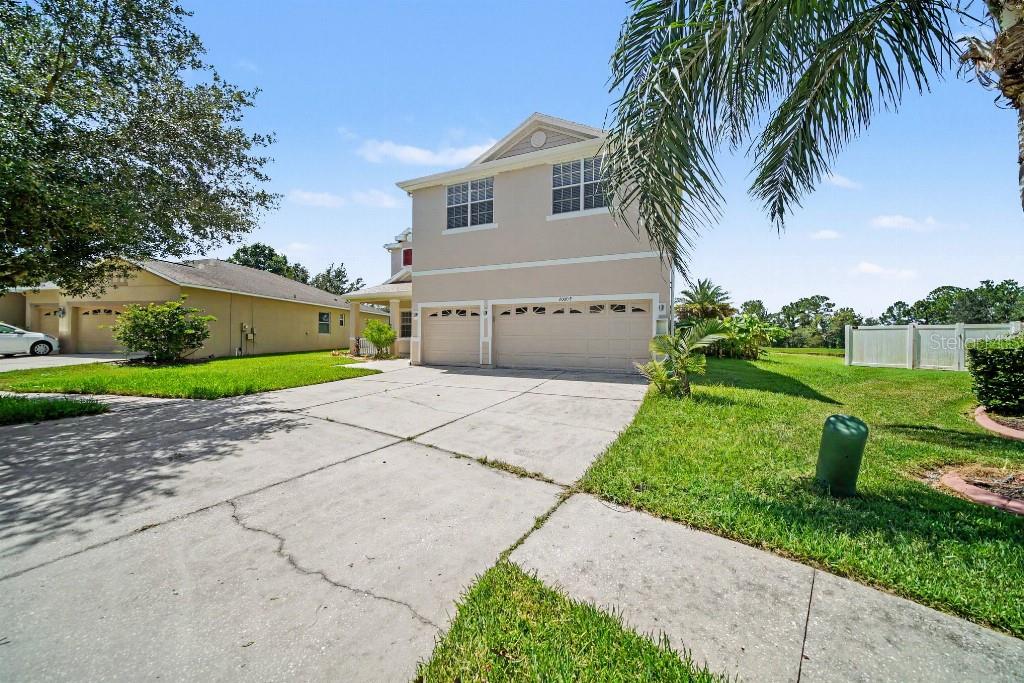 A two-story beige house with a three-car garage and a concrete driveway — 20009 OAKFLOWER AVENUE, TAMPA, FL