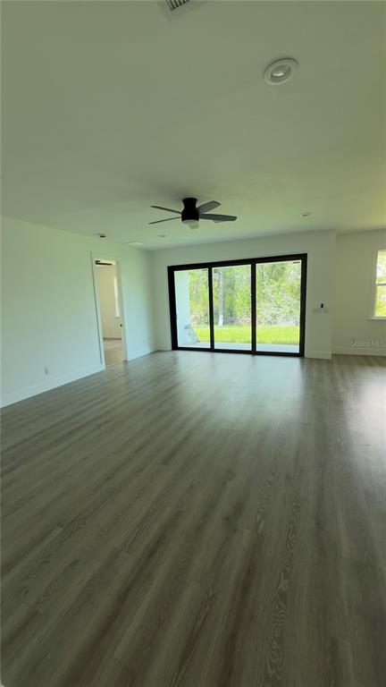 A spacious room with light wood-look flooring, a ceiling fan, and large sliding glass doors — 14300 SANILAC AVENUE, PORT CHARLOTTE, FL