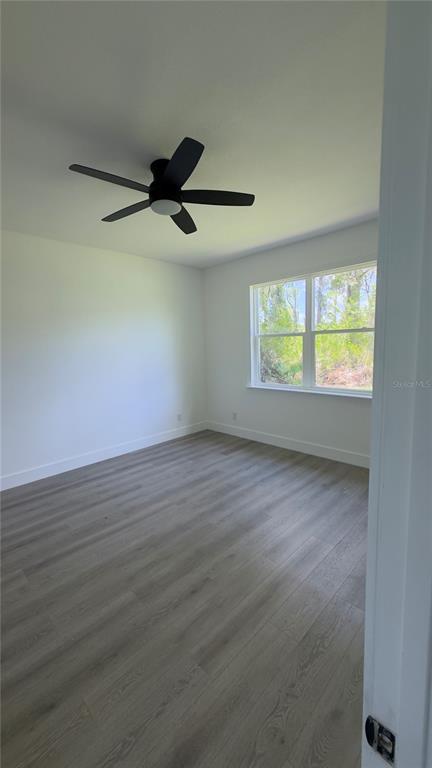 An empty bedroom features light gray wood-look flooring, white walls, and a black ceiling fan — 14300 SANILAC AVENUE, PORT CHARLOTTE, FL