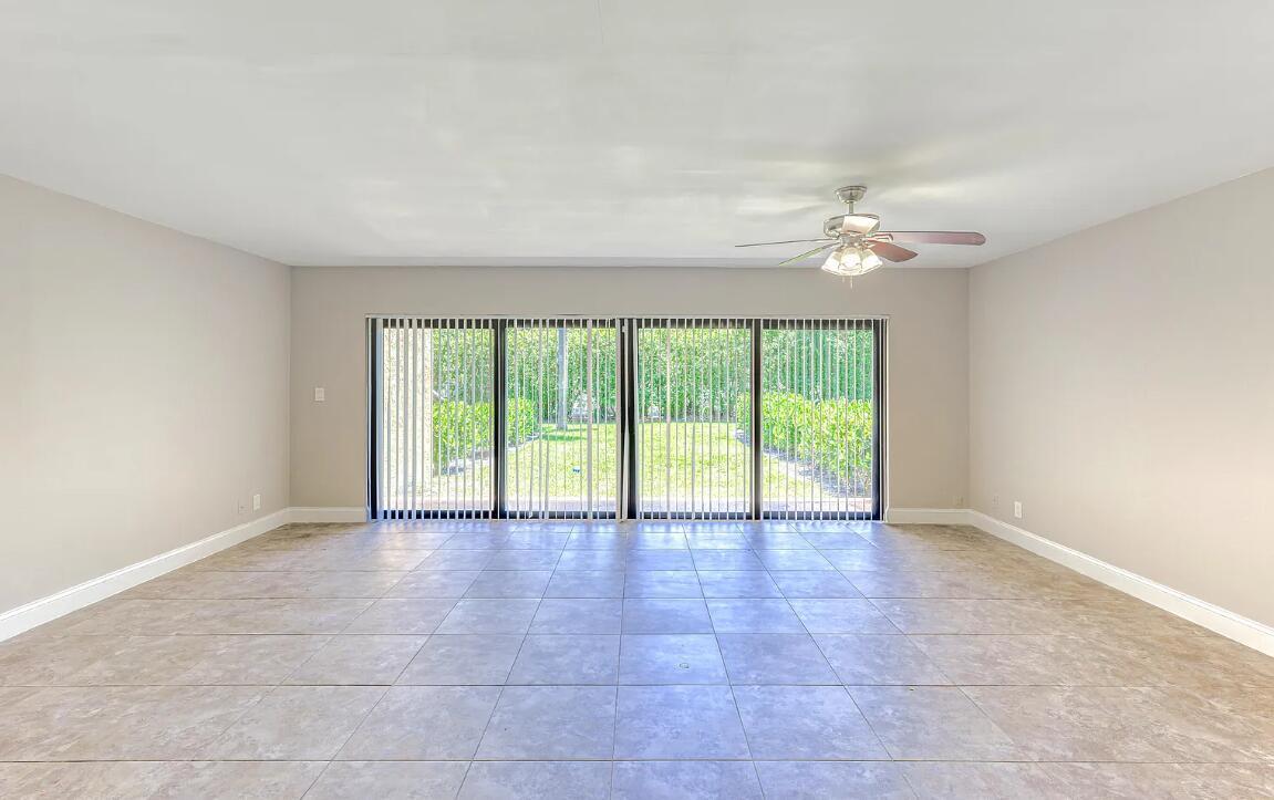 An empty room with light-colored tile flooring, beige walls, a ceiling fan, and sliding doors — 663 Dover Street # 10, Boca Raton FL 33487, BOCA RATON, FL
