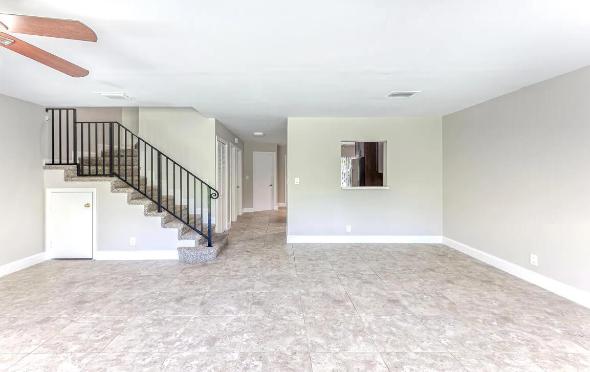 An open living area with tile floors, a carpeted staircase, and a kitchen pass-through window — 663 Dover Street # 10, Boca Raton FL 33487, BOCA RATON, FL