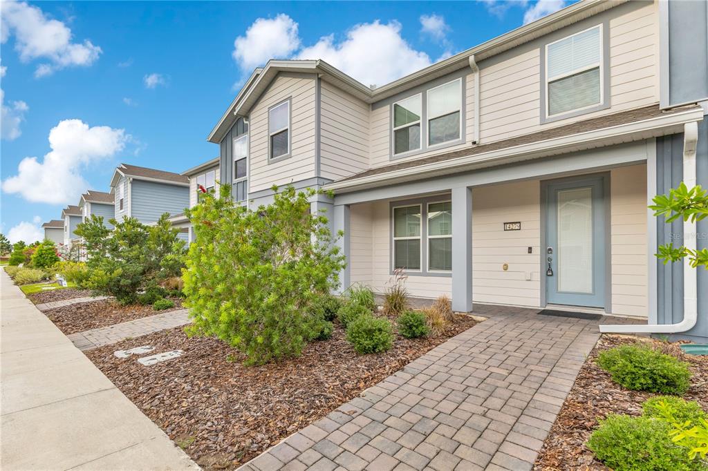 A row of two-story townhomes with light siding, paved walkways, and landscaped front yards — 14279 SAPELO BEACH DRIVE, ORLANDO, FL
