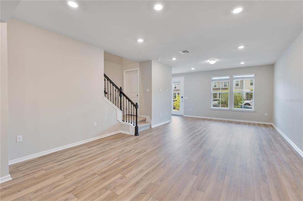 An open living area features light wood-look flooring, recessed lighting, and a staircase with railings — 14279 SAPELO BEACH DRIVE, ORLANDO, FL