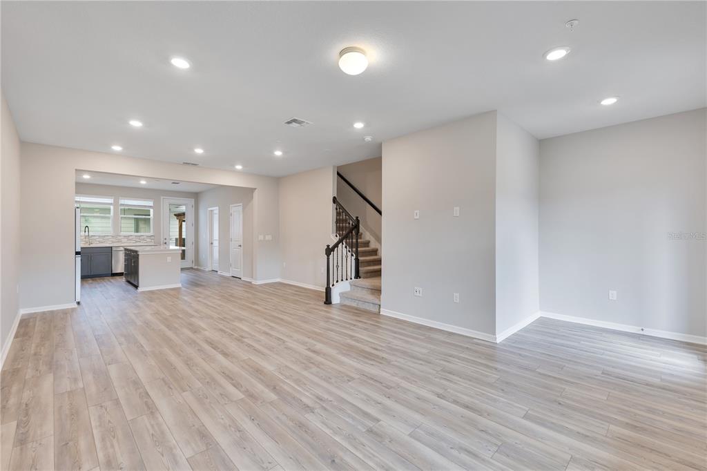 An open-concept living area features light wood-look flooring, recessed lighting, and a staircase — 14279 SAPELO BEACH DRIVE, ORLANDO, FL