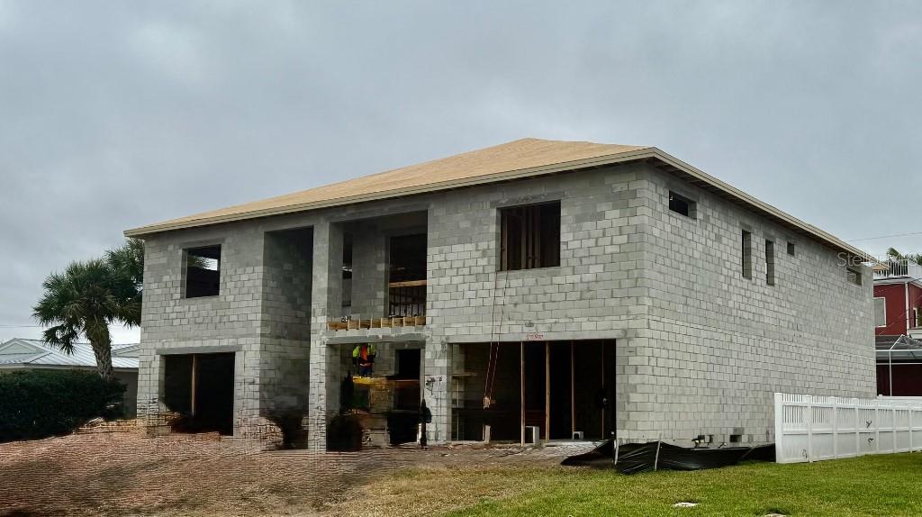 An unfinished two-story concrete block house under construction with a roof and open garage bays — 104 18TH STREET, BELLEAIR BEACH, FL