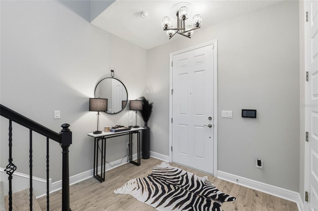 An entryway features light wood flooring, a white door, a console table, and a zebra rug — 7273 NOTCHED PINE BEND, WESLEY CHAPEL, FL