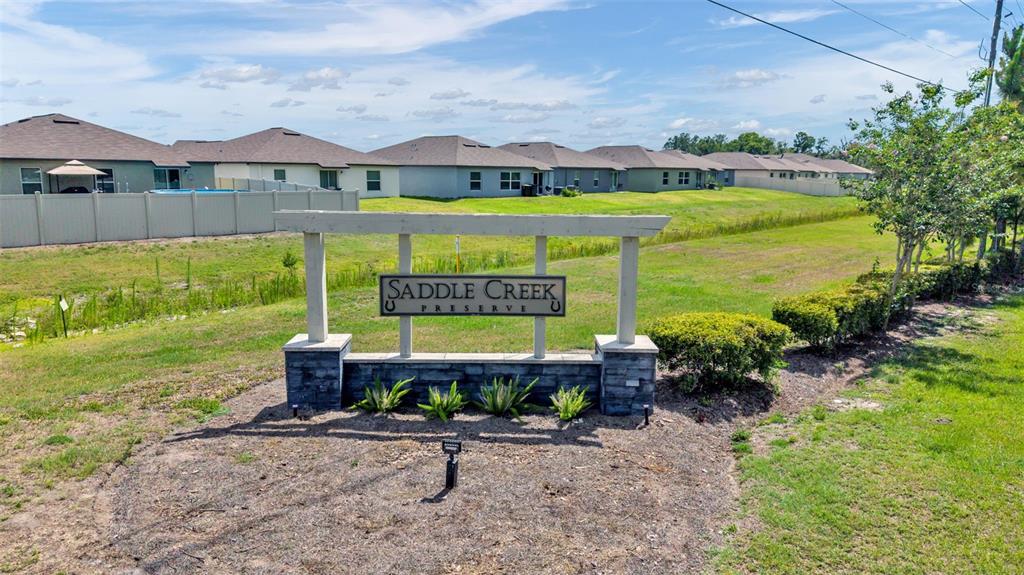 A stone and wood monument sign for Saddle Creek Preserve stands before a grassy field — 2063 OLD PASTURE LANE, LAKELAND, FL