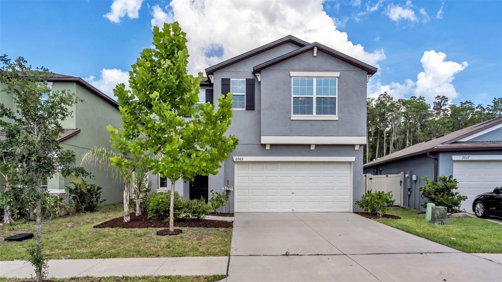 A two-story gray house with a two-car garage and a large tree in the yard — 2063 OLD PASTURE LANE, LAKELAND, FL