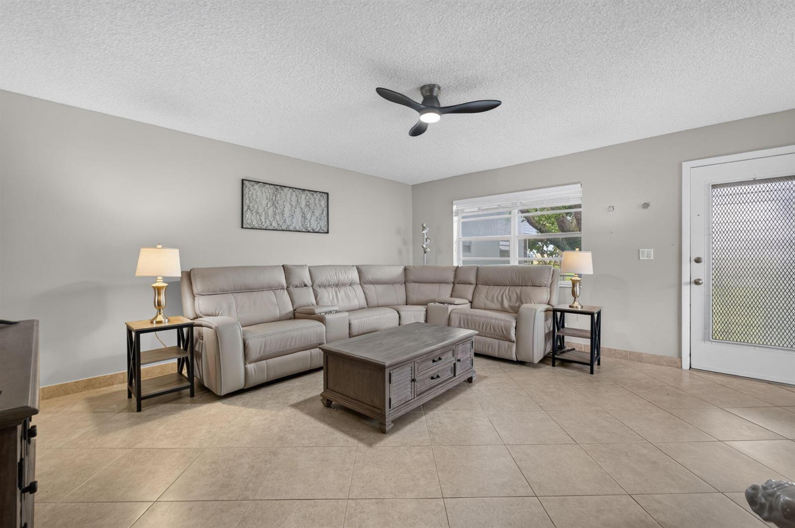 A living room with a beige sectional sofa, coffee table, and tile flooring — 942 Normandy T Trail # 942, Delray Beach FL 33484, DELRAY BEACH, FL