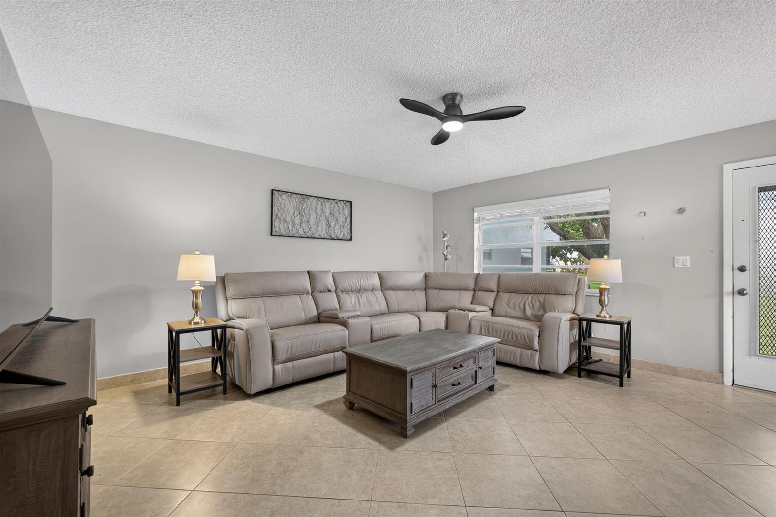 A living room features a beige sectional sofa, a coffee table, and tile flooring — 942 Normandy T Trail # 942, Delray Beach FL 33484, DELRAY BEACH, FL